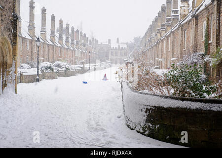 Nevicata presso la storica pietra miliare del vicario vicino e una giovane ragazza divertirsi sulla sua slitta. Pozzetti, Somerset, Regno Unito Foto Stock