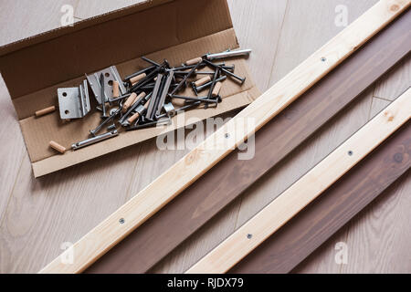 Accessori per mobili, di viti e di altre parti in open box craft sdraiato sul pavimento, montaggio di mobili a casa. Foto Stock