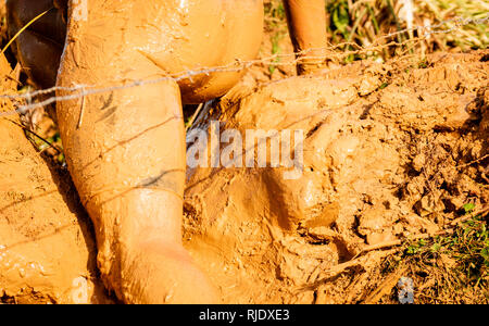 Trail Running atleta attraversando la pozzanghera sporca in un corridore di fango. Foto Stock