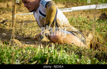 Gijon, Asturias, Spagna - Febbraio 04, 2019. Trail Running atleta attraversando la pozzanghera sporca in un corridore di fango. Foto Stock