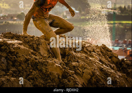 Trail Running atleta attraversando la pozzanghera sporca in un corridore di fango. Foto Stock