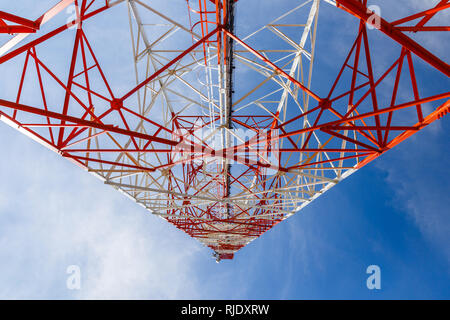 Vista dal basso di una torre per telecomunicazioni. rosso e bianco cellulare torre contro il cielo blu, vista dal basso Foto Stock