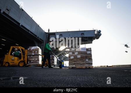 Golfo Arabico (GEN. 18, 2018) specialista della logistica marinaio reclutare Austin Hibbard utilizza un cric per pallet di movimentare pallet durante un rifornimento in mare a bordo della portaerei USS Theodore Roosevelt CVN (71). Theodore Roosevelt e il suo supporto strike gruppo sono distribuiti negli Stati Uniti Quinta Flotta area di operazioni a sostegno della sicurezza marittima operazioni per rassicurare gli alleati e partner e preservare la libertà di navigazione e il libero flusso di commercio nella regione. Foto Stock