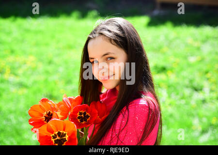 Fiori freschi recisi. Ragazza carina bambino con red tulip fiori in primavera. Bambina con bulbi da fiore fiorisce. Bella ragazza con il mazzo di fiori Foto Stock