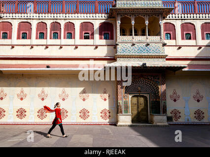 La donna in sciarpa rossa a piedi di piazza nel palazzo di città di Jaipur, Rajasthan, India Foto Stock
