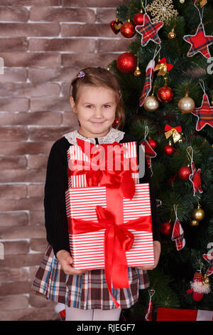 Carino toothsome ragazza elegante da indossare abiti casual felice godetevi il tempo di natale vacanze vicino al nuovo anno verde di pini albero decorato con accogliente giocattoli tenere premuto Foto Stock