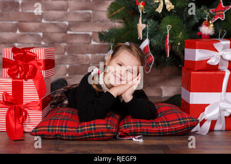 Carino toothsome ragazza elegante da indossare abiti casual felice godetevi il tempo di natale vacanze vicino al nuovo anno verde di pini albero decorato con accogliente giocattoli tenere premuto Foto Stock