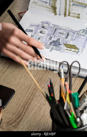 Messa a fuoco selettiva dei womans mani thumbing sketchbook sul tavolo di legno Foto Stock