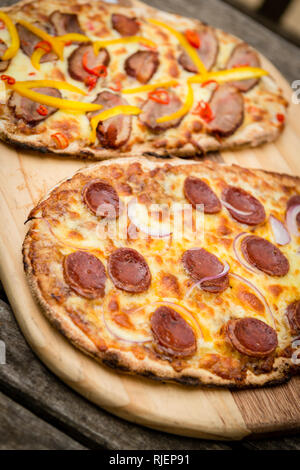 Fare la pizza a casa e casalingo di salsiccia per pizza pizza con le cipolle e peperoni Foto Stock