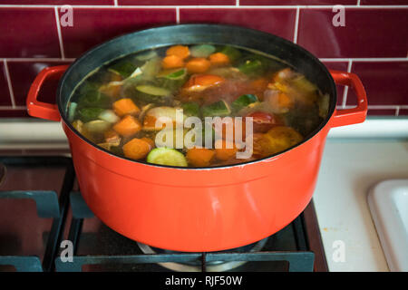 Rosso con pot bollente zuppa vegetale sulla stufa in cucina di borgogna. Foto Stock