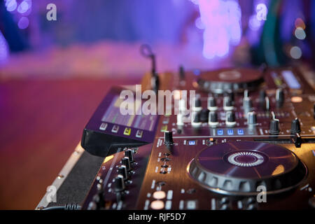 Disc jockey mixare musica sul digitale midi controller giradischi al hip hop party sul palco in night club.Mani di DJ giocare mostrano tracce di miscelazione sul mixer su Foto Stock