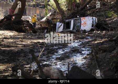 Un auto è ribaltata e un quartiere superamento con fango come primi responder e soldati da la 315costruzione verticale Company, California Esercito Nazionale Guardia, opera al fine di rimuovere i detriti, gen. 13, 2018 a Montecito, California. Il gruppo ha lavorato per scavare nelle case e strade a seguito di una frana di fango devastanti Gen 9 che ha ucciso almeno 20 persone, case distrutte e quartieri di sinistra tagliata. Foto Stock