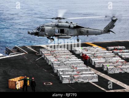 Un HH-60H Sea Hawk elicottero assegnato per gli Indiani di elicottero anti-sommergibile Squadron 6 airlifts ordnance off il ponte di volo della portaerei USS Nimitz durante un offload di munizioni con la forza militare di comando Sealift carichi secchi e munizioni nave USNS Wally Schirra. Nimitz sta conducendo acqua blu le operazioni negli Stati Uniti La terza area della flotta di responsabilità. Foto Stock