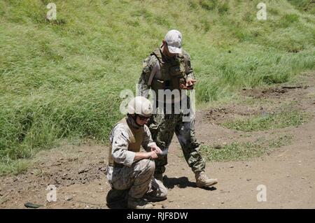 Capo l'eliminazione degli ordigni esplosivi Michael Solis di Camden, N.J., un membro della superficie navale Warfare Center, Indian Head l'eliminazione degli ordigni esplosivi divisione Technology lancia segnali cpl. Ryan Morgan di Dixon, California, un uomo di ricognizione con forza di 4 società di ricognizione, primo plotone, per innescare un colpo di tempo il fusibile collegato ad un blocco di C4 esplosivo durante la demolizione di formazione presso la Baia di Kaneohe gamma Training Facility 20 Agosto, 2014. Solis, un'eliminazione degli ordigni esplosivi e esperto di demolizioni, hanno contribuito ad aumentare la forza di 4 società di ricognizione per le due settimane di formazione annuale periodo come parte di un Foto Stock