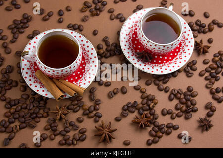 Due piccante di caffè nero polka dot tazze e i chicchi di caffè pasticcio su sfondo marrone Foto Stock