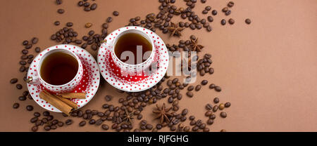 Due piccante di caffè nero polka dot tazze e i chicchi di caffè pasticcio su sfondo marrone banner spazio di copia Foto Stock