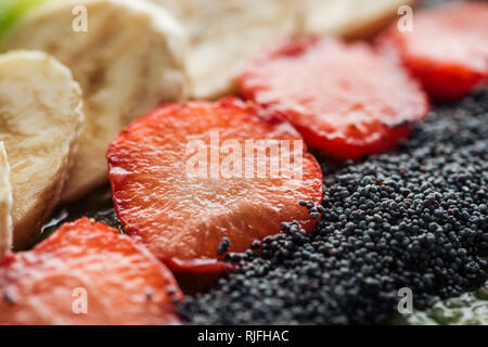 Messa a fuoco selettiva di fettine di banane biologiche, fragole e semi di papavero Foto Stock