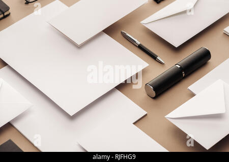 Penna, caso, buste e fogli di carta su sfondo beige Foto Stock