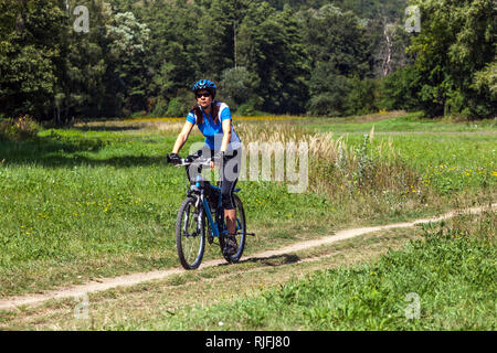 Ciclista donna in un viaggio nel prato del fiume Dyje, in bicicletta, nel parco nazionale di Podyji, nella Moravia meridionale, sulla pista ciclabile della Repubblica Ceca Foto Stock