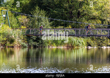 I ciclisti fanno un giro su un ponte pedonale che attraversa il fiume Dyje nel parco nazionale di Podyji, Moravia meridionale, Repubblica Ceca Foto Stock