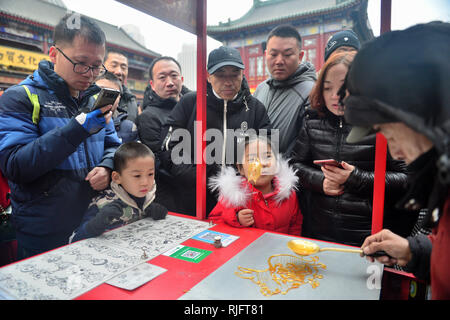 Tianjin. 5 febbraio, 2019. I turisti di guardare un popolare artista fare lo zucchero pittura presso l antica strada culturale di Tianjin, Cina del nord, Febbraio 5, 2019, il primo giorno del nuovo anno lunare cinese. Credito: Hu Lingyun/Xinhua/Alamy Live News Foto Stock