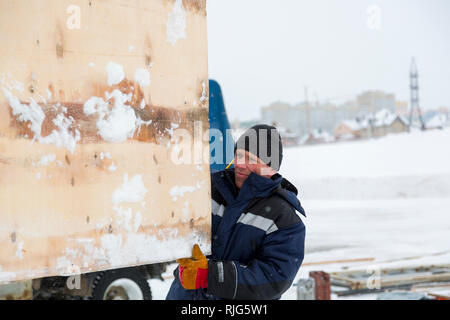 Lavoratore in una giacca blu con una cappa e un nero berretto lavorato a maglia sulla sua testa Foto Stock