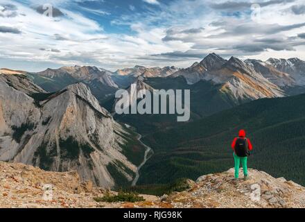 Escursionista femmina guarda dal vertice oltre il paesaggio di montagna, vertice con orange depositi di zolfo, Vista panoramica Foto Stock