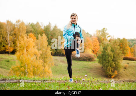 Che corre lungo un percorso di parcheggio, assistenza sanitaria e problema concetto - close-up di un infelice persona che soffre di un dolore alla gamba o al ginocchio all'aperto Foto Stock