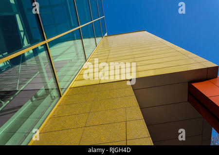 Forme geometriche di un moderno edificio di vetro e pietra contro il cielo blu chiaro Foto Stock