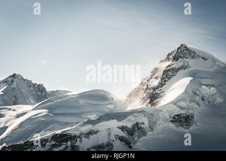 Luce dorata si rompe sulla neve oltre il maestoso picco Jungfrau visto dalla parte superiore dell'Europa, Jungfraujoch, Svizzera Foto Stock