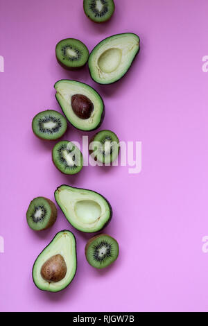 Tagliate gli avocadi e kiwi su uno sfondo rosa Foto Stock