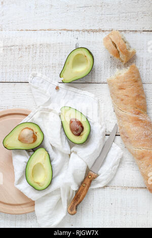 Fette di avocado e ciabatta pane su un bianco tavolo in legno Foto Stock