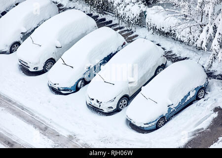 Auto coperti di neve con i tergicristalli sollevata in un parcheggio in inverno Foto Stock