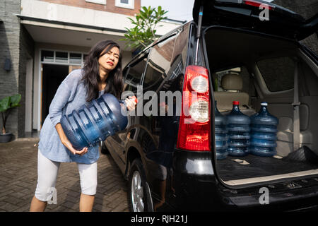 Sconvolto donna provare a portare il gallone di acqua Foto Stock