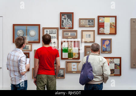 Tre persone che guardano le opere su una parete Foto Stock