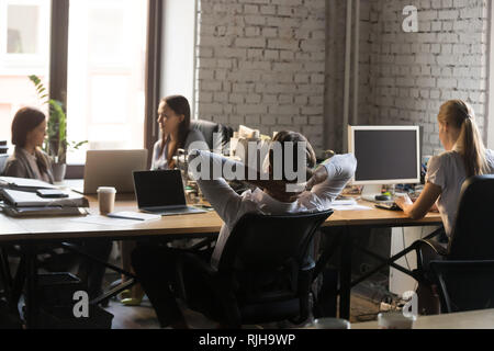 Stanco dipendente rilassarvi in poltrona che lavorano in ufficio condiviso Foto Stock