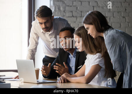 Diversi lavoratori millenario collaborando al laptop insieme Foto Stock