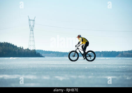 Uomo in bicicletta su un lago ghiacciato Foto Stock