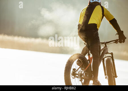 Uomo in bicicletta su un lago ghiacciato Foto Stock