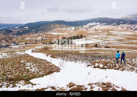 Amici a piedi attraverso una coperta di neve campo in inverno Foto Stock