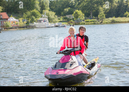 Madre e figlio adolescente su jet ski Foto Stock