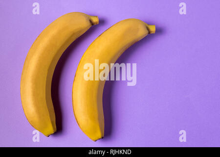 Il minimalismo creativi concetto. Concetto di imprevisti. Appartamento vista laici di banana frutto pattern su sfondo viola. Foto Stock