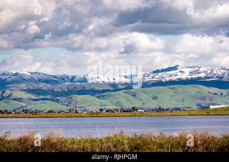 Vista panoramica verso il verde delle colline e montagne innevate in una fredda giornata invernale presi dalle rive di un laghetto nella parte sud di San Francisco Bay Area; San Jose, Foto Stock