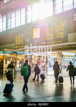 Torino, Italia - Gennaio 1, 2019. I viaggiatori sotto un digital display orario in una sala della stazione ferroviaria di Porta Nuova. Torino Piemonte, Italia. Foto Stock