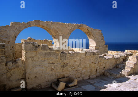 Palazzo del vescovo rimane, antica Kourion, Episkopi, Distretto di Limassol, Cipro: twin archi di pietra contro il blu del Mediterraneo Foto Stock