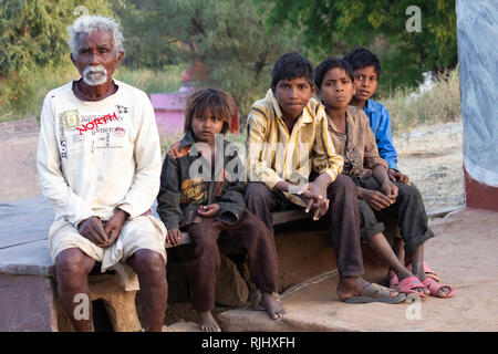 Tribù Bhil. Un uomo anziano si siede con quattro giovani ragazzi nel loro villaggio vicino Bhainsrorgargh, Rajasthan, India. Foto Stock