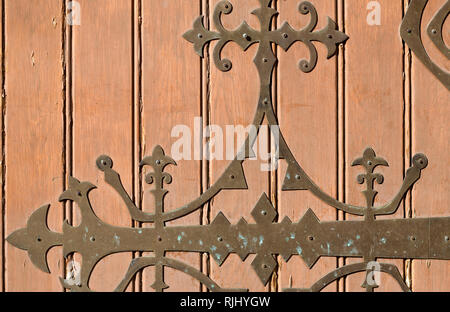 Luce marrone porta in legno con metallo forgiato il motivo di un vecchio tempio nella giornata di sole Foto Stock