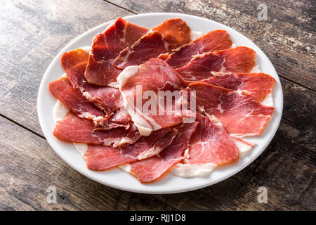 Lo spagnolo prosciutto Serrano o prosciutto in piastra su un tavolo di legno sul tavolo di legno Foto Stock