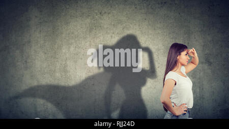 Vista laterale di una giovane donna di immaginare di essere un super eroe cerca aspirava. Foto Stock