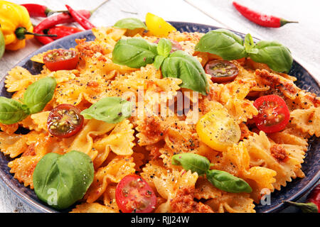 Farfalle. Deliziosa crema di penne italiani pasta starter con condimento di pepe e basilico fresco visto dal di sopra su rustiche. Foto Stock